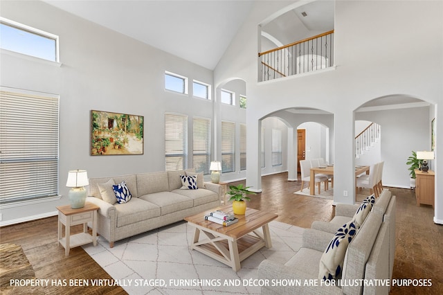 living room with a towering ceiling, light hardwood / wood-style flooring, and a healthy amount of sunlight