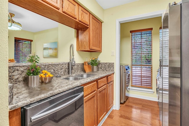 kitchen featuring a wealth of natural light, sink, light hardwood / wood-style floors, stainless steel appliances, and washer and clothes dryer