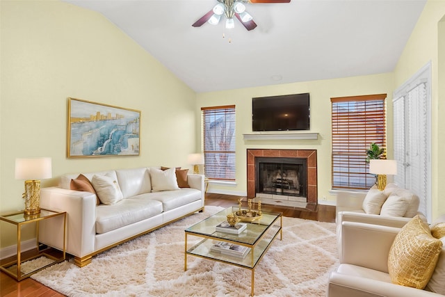 living room with ceiling fan, lofted ceiling, hardwood / wood-style floors, and a tile fireplace