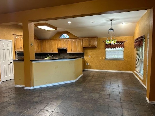 kitchen with lofted ceiling, decorative light fixtures, stainless steel microwave, and decorative backsplash