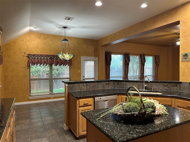 kitchen with vaulted ceiling, pendant lighting, sink, dark stone countertops, and stainless steel dishwasher