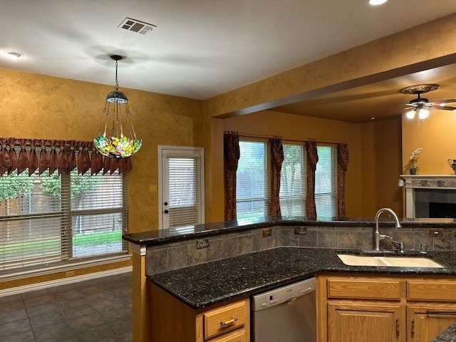 kitchen with sink, dishwasher, hanging light fixtures, a healthy amount of sunlight, and dark stone counters