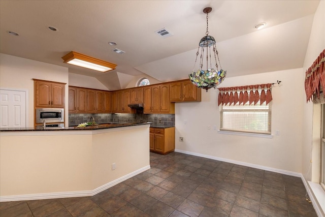 3108 Fernhurst Dr, Richardson, TX 75082 - kitchen featuring stainless steel microwave, vaulted ceiling, visible vents, backsplash, and brown cabinets