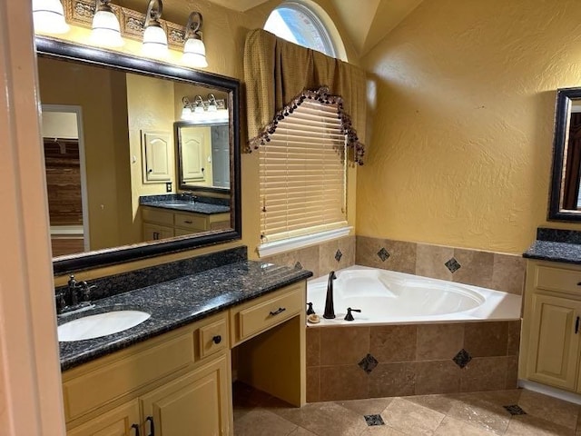 bathroom featuring tile patterned floors, vanity, and tiled tub