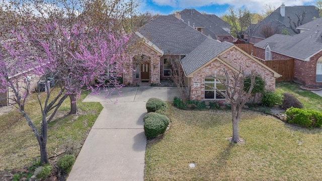 3108 Fernhurst Dr, Richardson, TX 75082 - view of front of property featuring roof with shingles, stone siding, fence, brick siding, and a front yard