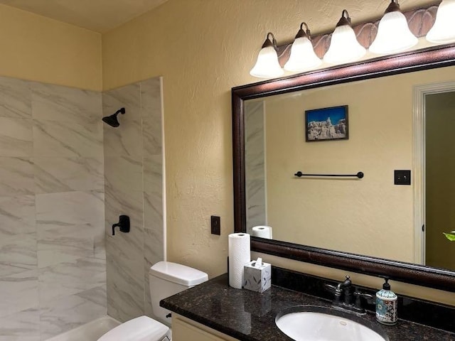 bathroom featuring vanity, toilet, and a tile shower