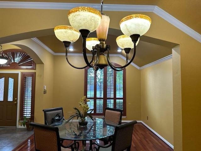 dining area with dark wood-type flooring, ornamental molding, and a notable chandelier