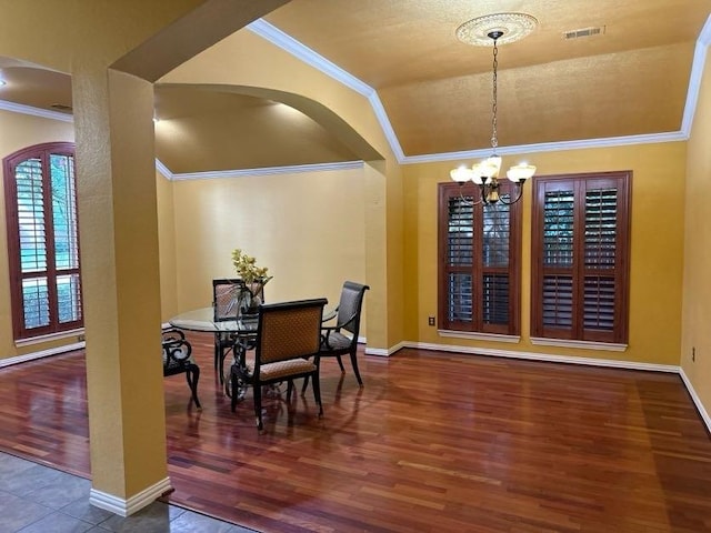 dining room with ornamental molding, lofted ceiling, wood-type flooring, and a notable chandelier