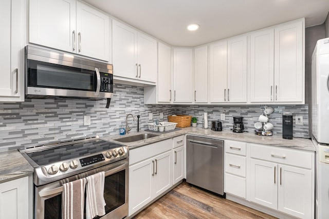 kitchen with white cabinetry, sink, stainless steel appliances, and light stone countertops