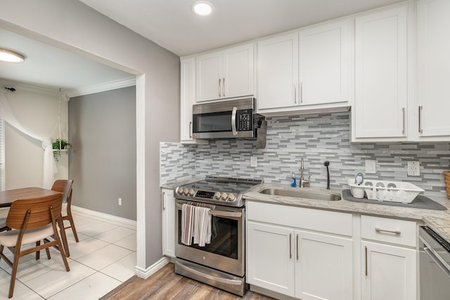 kitchen featuring tasteful backsplash, sink, white cabinets, and appliances with stainless steel finishes