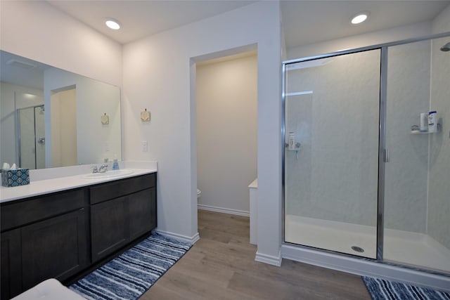 bathroom featuring a shower with door, vanity, hardwood / wood-style floors, and toilet