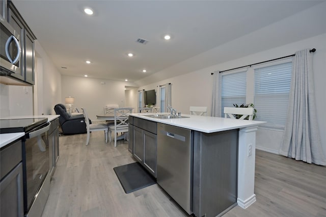 kitchen with sink, a center island with sink, light hardwood / wood-style flooring, appliances with stainless steel finishes, and gray cabinets