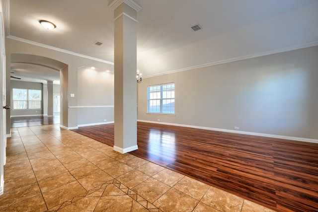 unfurnished room with ornate columns, crown molding, a wealth of natural light, and light tile patterned floors