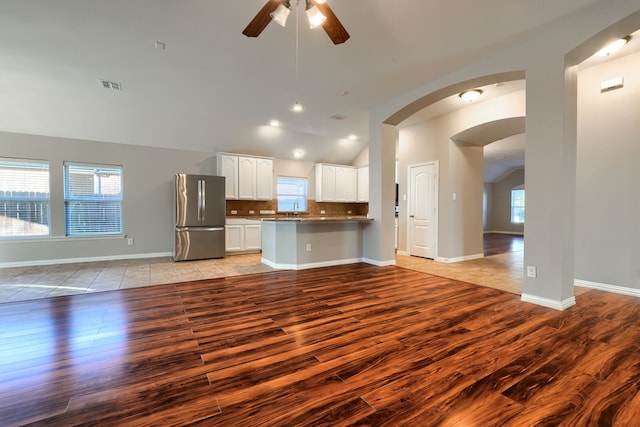 kitchen with stainless steel refrigerator, sink, backsplash, white cabinets, and kitchen peninsula