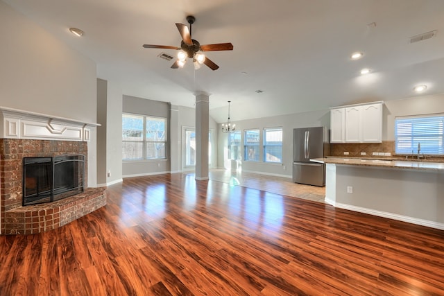 unfurnished living room with a healthy amount of sunlight, sink, a brick fireplace, and light hardwood / wood-style flooring