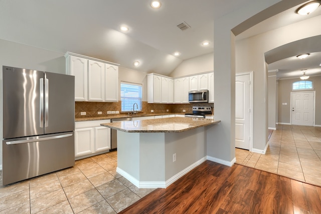 kitchen with sink, white cabinets, a center island, stainless steel appliances, and light stone countertops