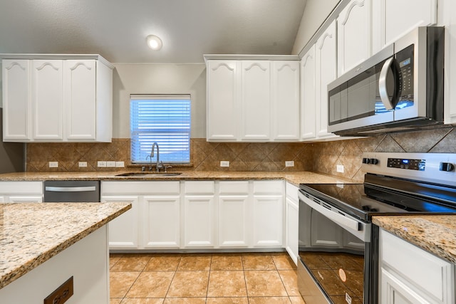 kitchen with sink, light stone countertops, white cabinets, and appliances with stainless steel finishes