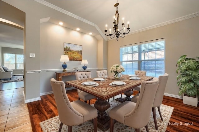 dining space with an inviting chandelier, hardwood / wood-style floors, ornamental molding, and lofted ceiling