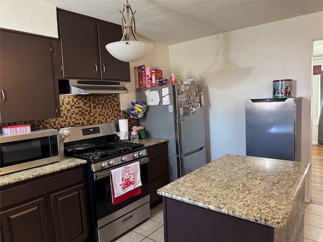 kitchen with a textured ceiling, a kitchen island, pendant lighting, stainless steel appliances, and decorative backsplash