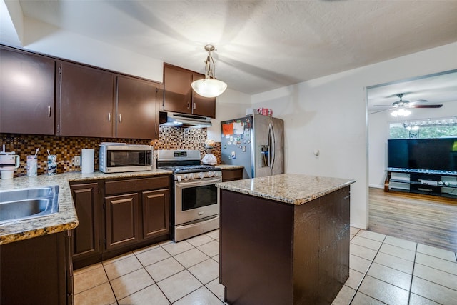 kitchen with dark brown cabinets, hanging light fixtures, light tile patterned floors, appliances with stainless steel finishes, and a kitchen island