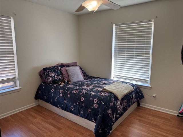 bedroom with ceiling fan, multiple windows, and light wood-type flooring