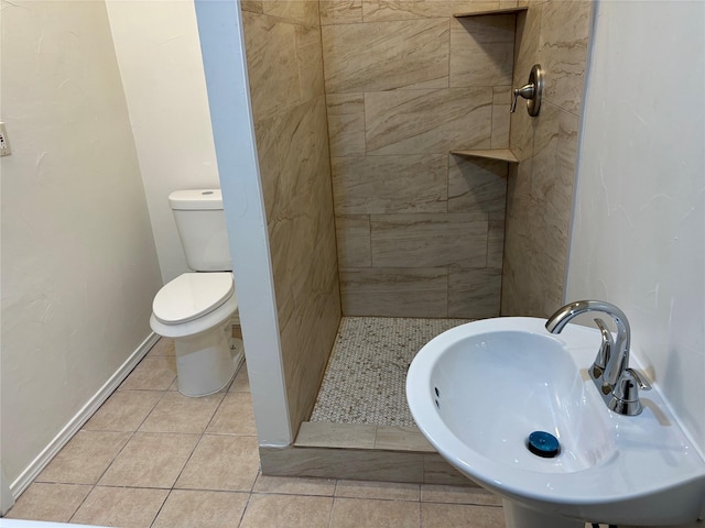 bathroom with sink, tiled shower, tile patterned floors, and toilet