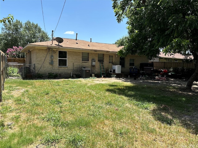 rear view of property featuring central AC and a lawn