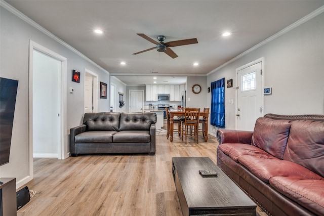 living room with ceiling fan, ornamental molding, and light hardwood / wood-style flooring