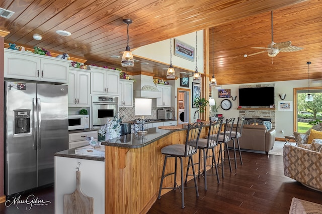 kitchen with white cabinetry, wood ceiling, stainless steel appliances, and a kitchen bar