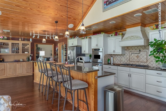 kitchen with appliances with stainless steel finishes, an island with sink, white cabinetry, custom exhaust hood, and wood ceiling