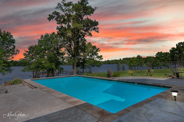 pool at dusk with a patio area