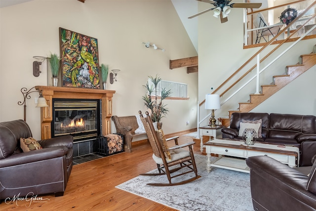 living room with hardwood / wood-style flooring, a high ceiling, ceiling fan, and beamed ceiling