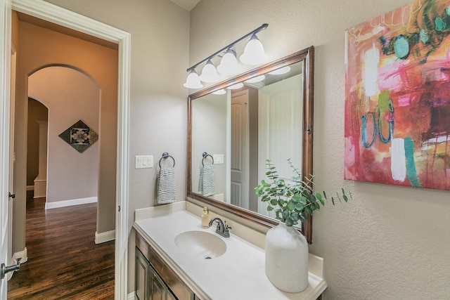 bathroom featuring baseboards, a textured wall, vanity, and wood finished floors