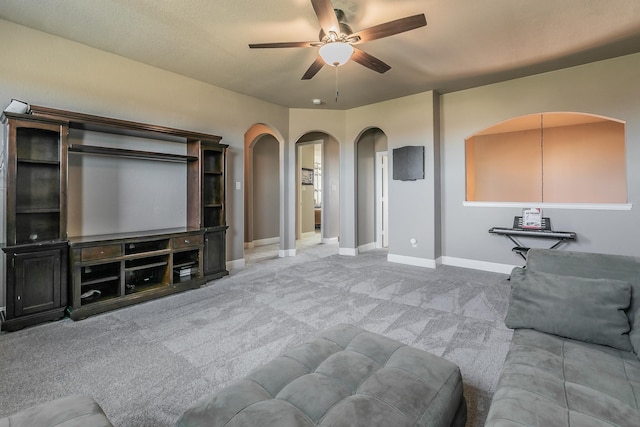 living area featuring ceiling fan, arched walkways, carpet flooring, and baseboards
