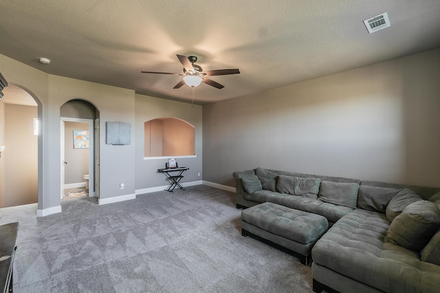 carpeted living area featuring baseboards, a ceiling fan, visible vents, and arched walkways