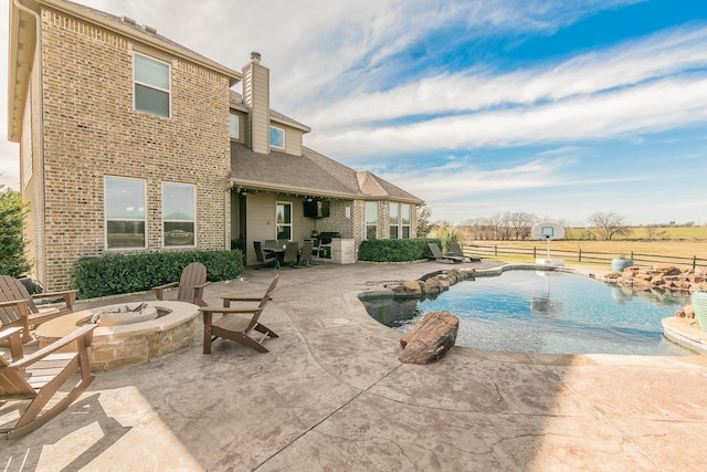 view of pool with a patio, pool water feature, and a fire pit