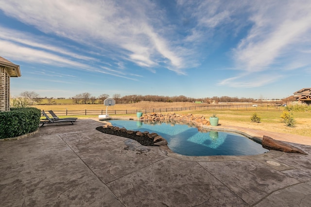 view of swimming pool with a rural view and a patio area