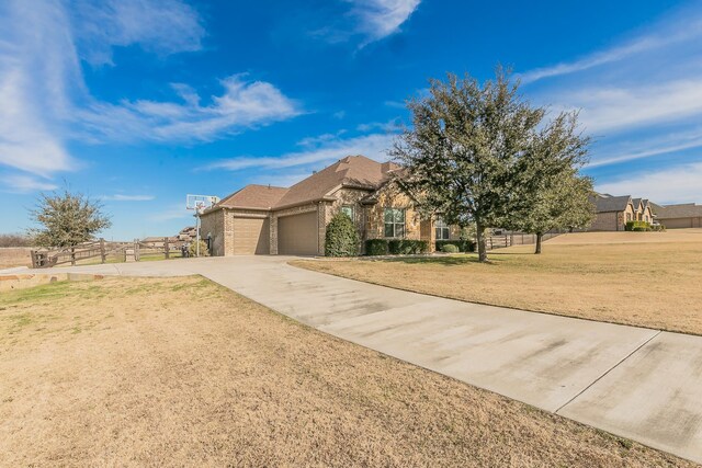 view of front facade featuring a front lawn, concrete driveway, fence, brick siding, and an attached garage