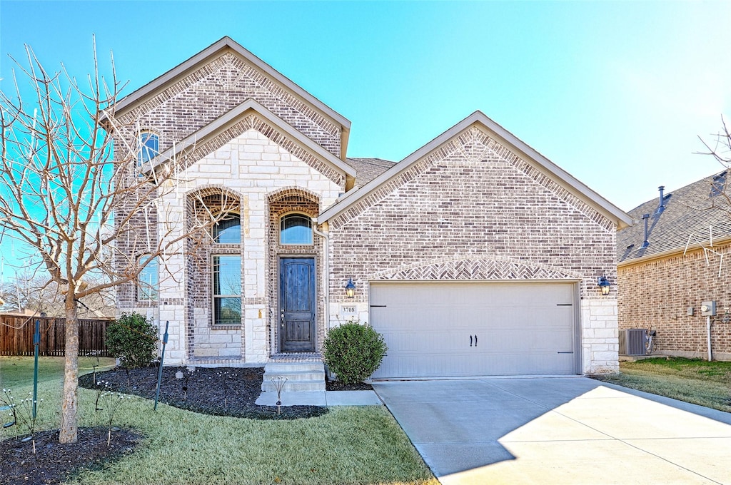 view of front of house with a garage, central AC unit, and a front lawn