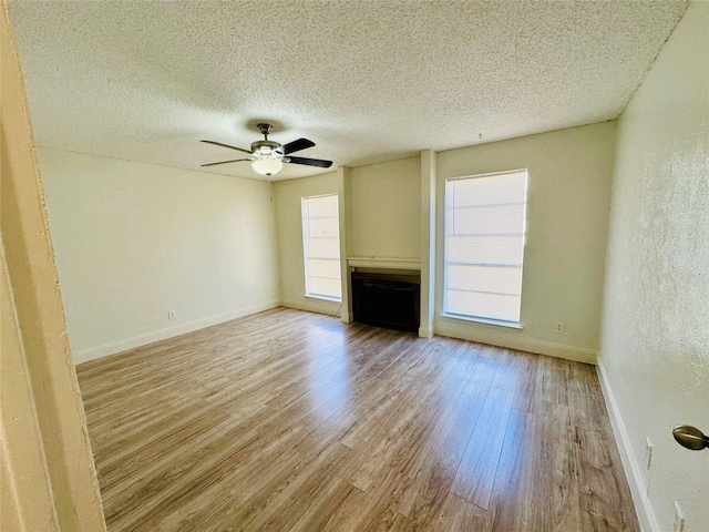 interior space with ceiling fan, plenty of natural light, a textured ceiling, and light wood-type flooring