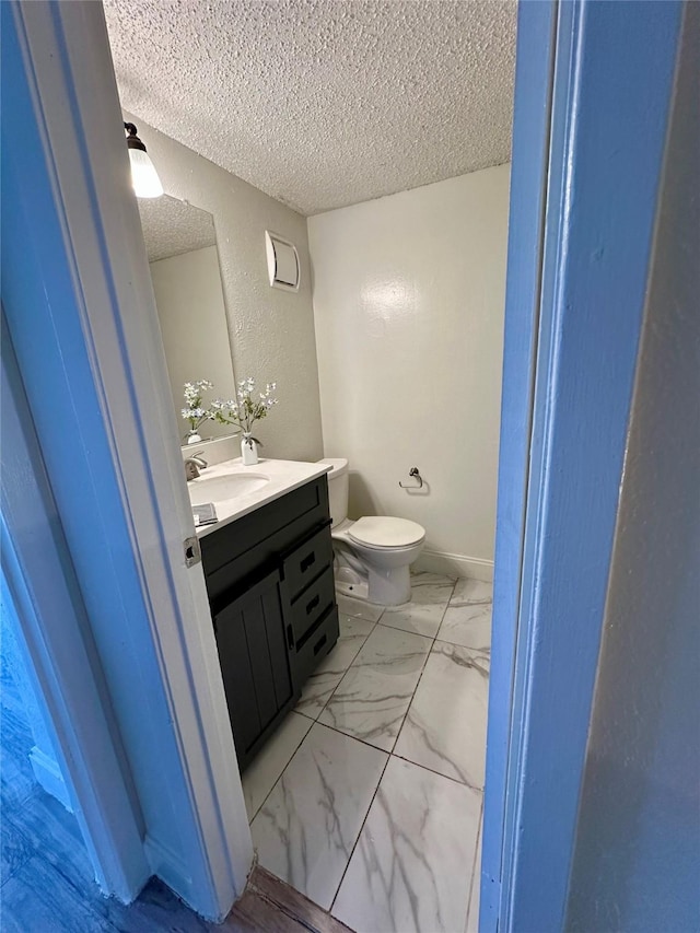 bathroom featuring vanity, toilet, and a textured ceiling