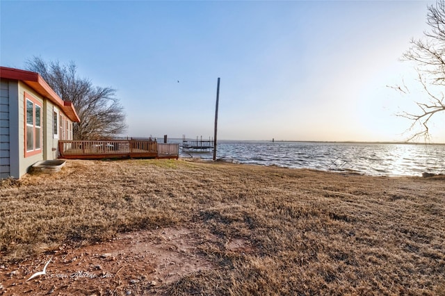 yard at dusk featuring a deck with water view