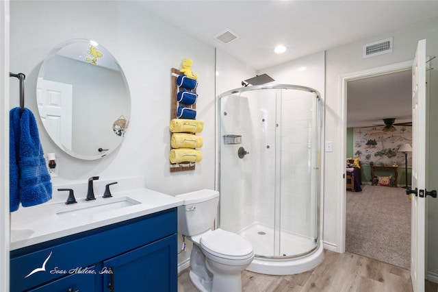 bathroom with hardwood / wood-style flooring, vanity, toilet, and a shower with shower door