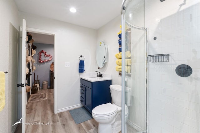 bathroom featuring a shower with door, vanity, hardwood / wood-style floors, and toilet