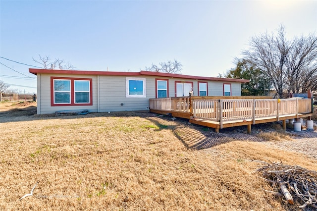 rear view of property featuring a deck and a lawn