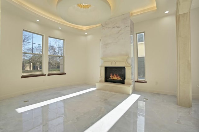 unfurnished living room featuring a high end fireplace and a tray ceiling