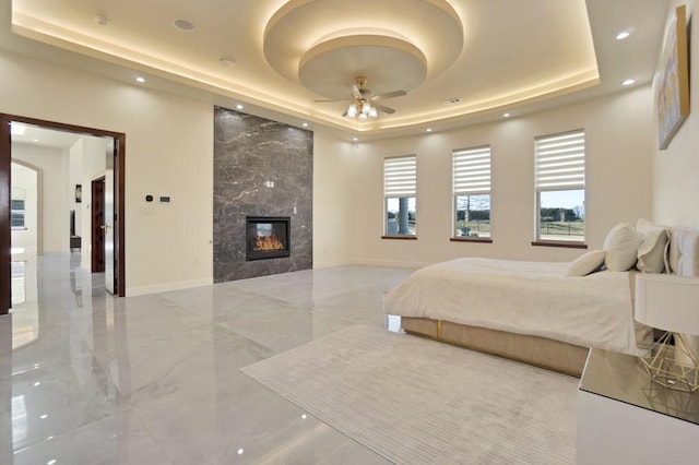 bedroom with a high end fireplace and a tray ceiling