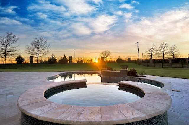 pool at dusk with a yard and a patio area