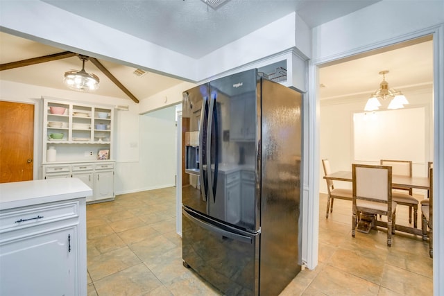 kitchen featuring lofted ceiling, black fridge, hanging light fixtures, a notable chandelier, and white cabinets