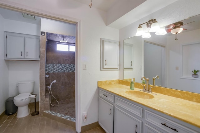 bathroom featuring vanity, tiled shower, and toilet